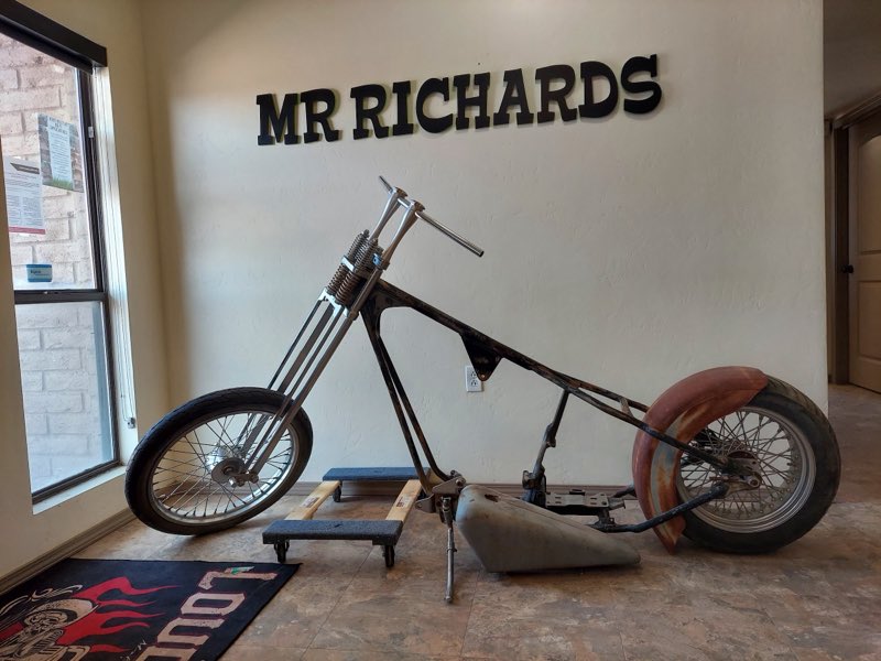 Custom chopper build in progress beneath the MR RICHARDS wall lettering inside the shop